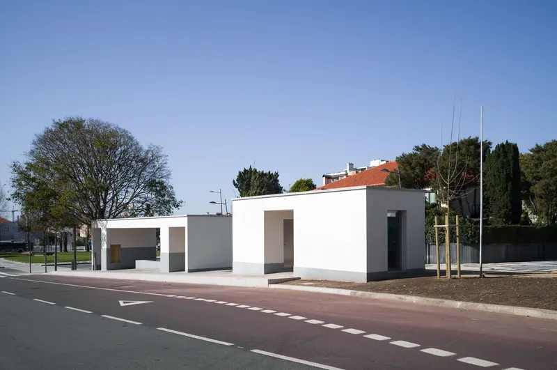 Street view of white cubic pavilion volumes with square openings along the roadway