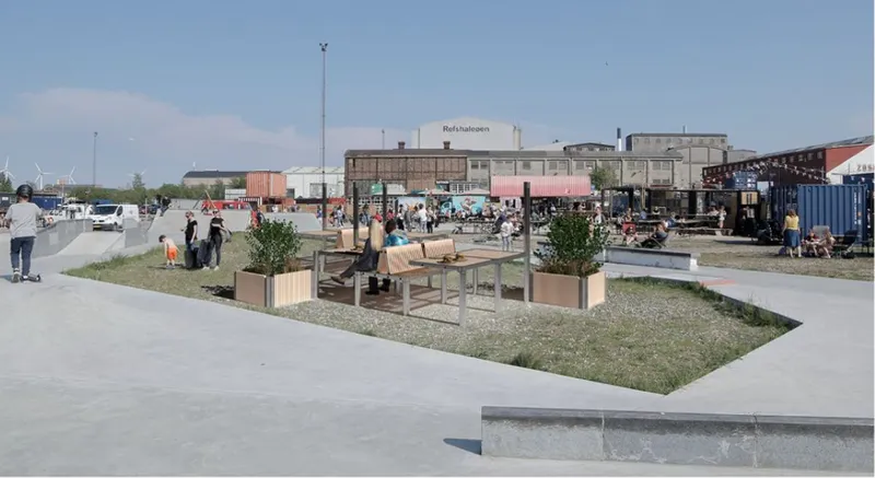 Public plaza with timber benches and planted boxes in a gravel area with industrial buildings beyond