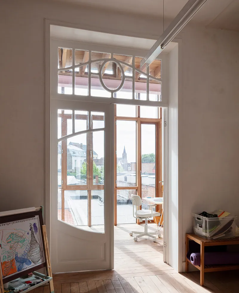 Open doorway with decorative transom window framing a view onto a terrace with timber doors
