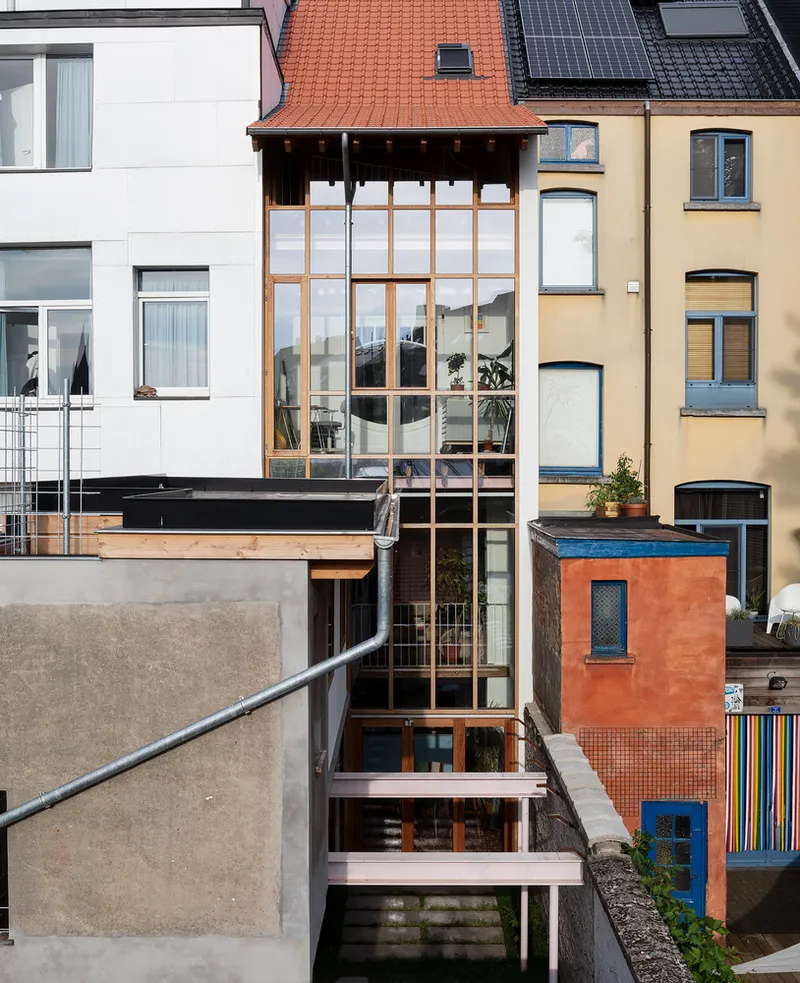 Rear facade showing stacked terraces with steel frames and full-height glazed bay between adjacent rowhouses