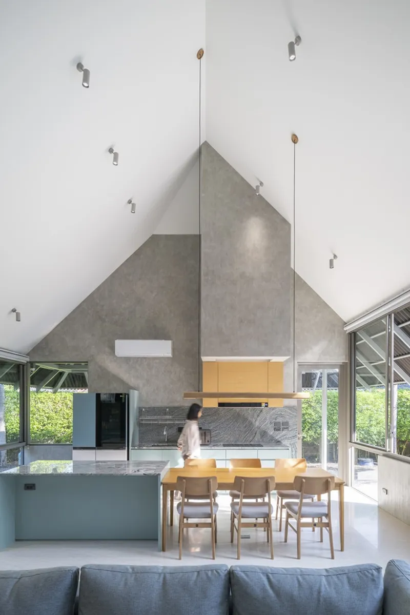 Interior view of the dining area with pitched concrete ceiling and a person moving through the space