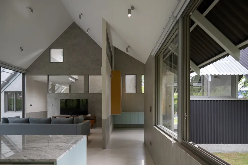 Double-height living space with gabled concrete walls and full-height glazing to the courtyard