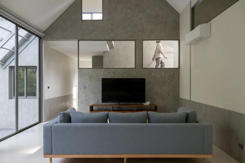 Living room with a concrete wall featuring clerestory openings to the upper level