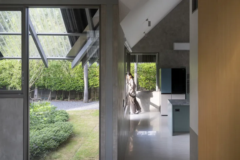 Hallway view through glazed doors opening to a lawn courtyard with bamboo screening