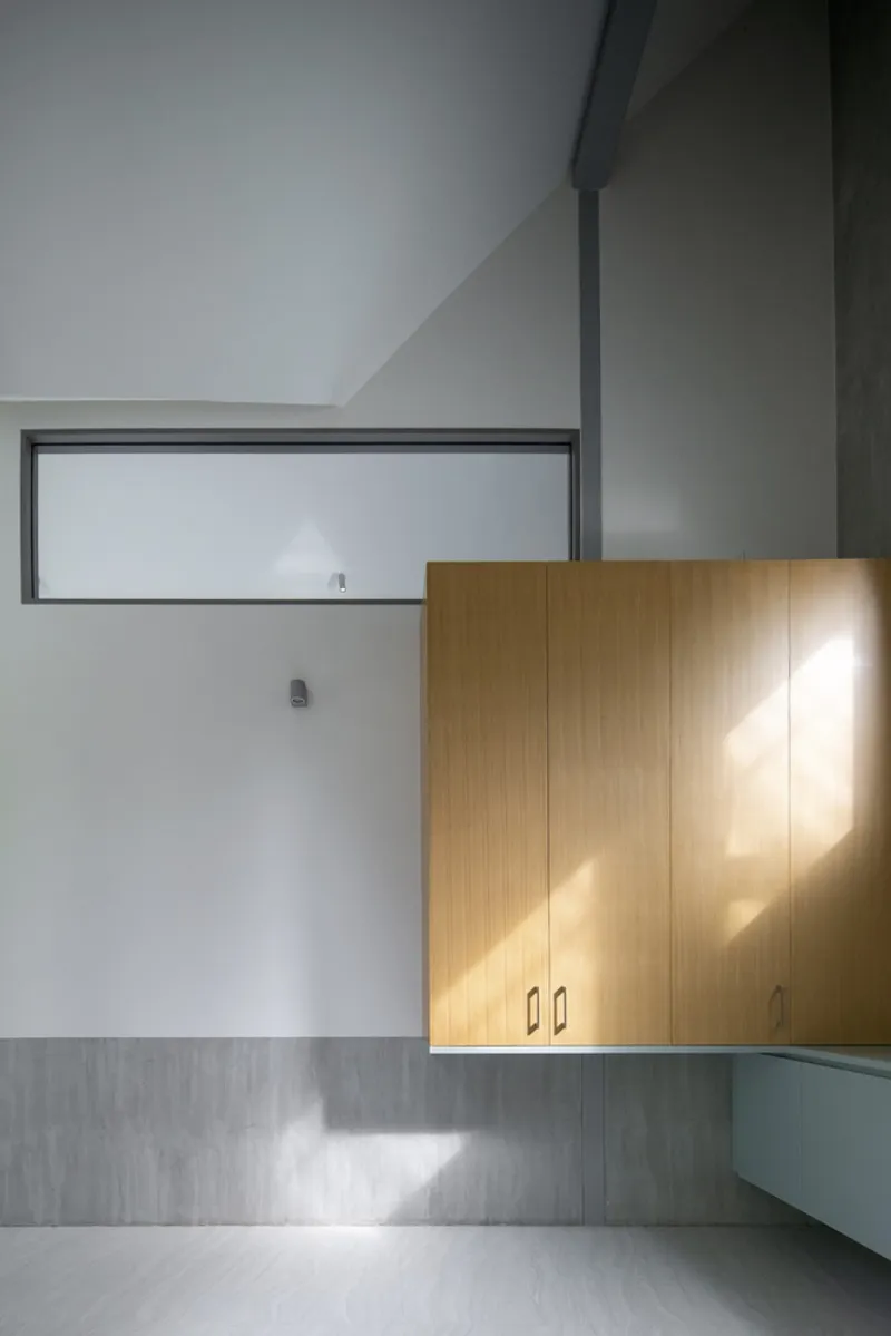 Timber cabinetry beneath a horizontal clerestory window catching afternoon sunlight