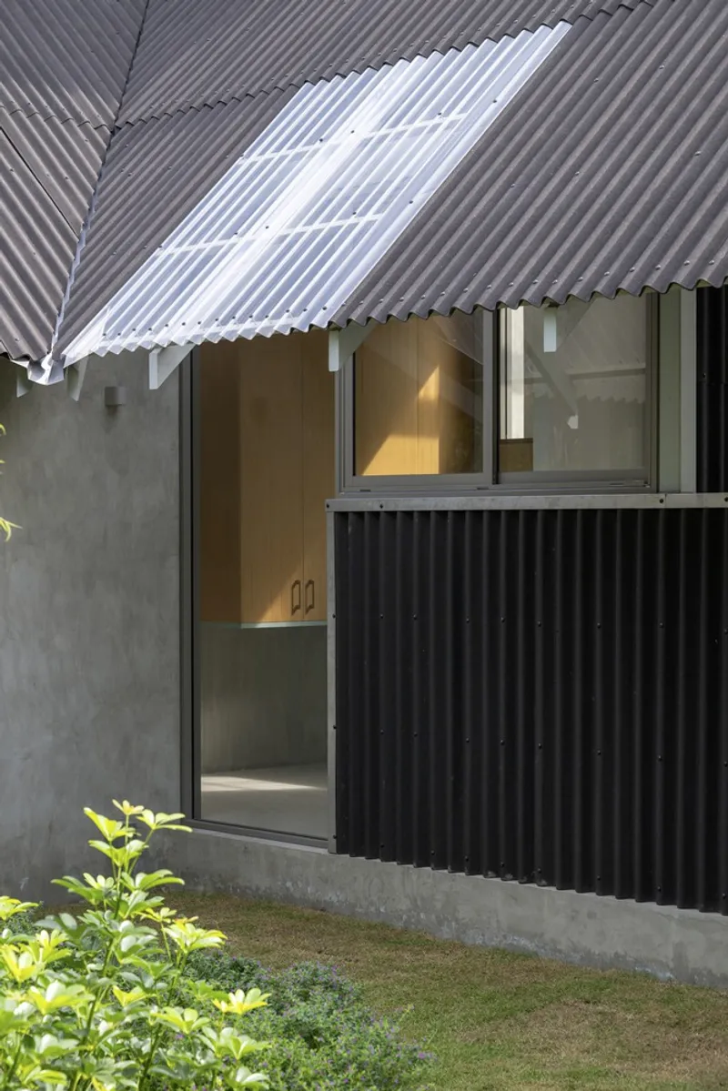 Courtyard view of corrugated metal cladding and translucent roof overhang with planted edge