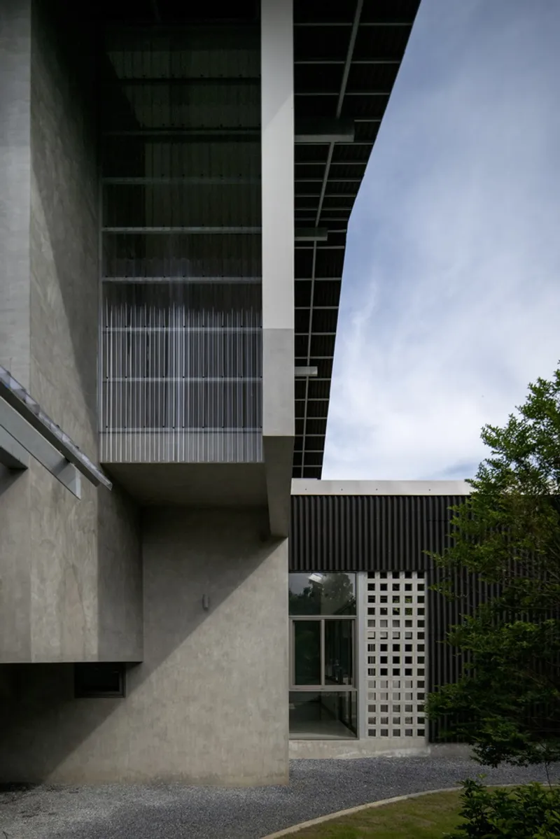 Stacked concrete masses and vertical metal slat screen beneath the cantilevered gridded canopy