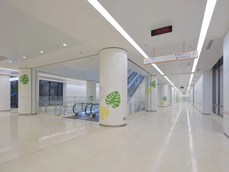 Interior lobby corridor with curved white columns, recessed linear lighting and leaf graphic appliqués