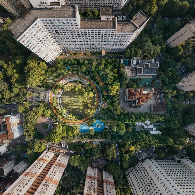 Drone view of the ring-shaped structure surrounded by dense greenery and apartment blocks