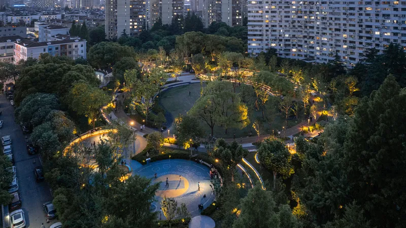 Aerial view of the illuminated circular park pavilion nestled among trees at dusk