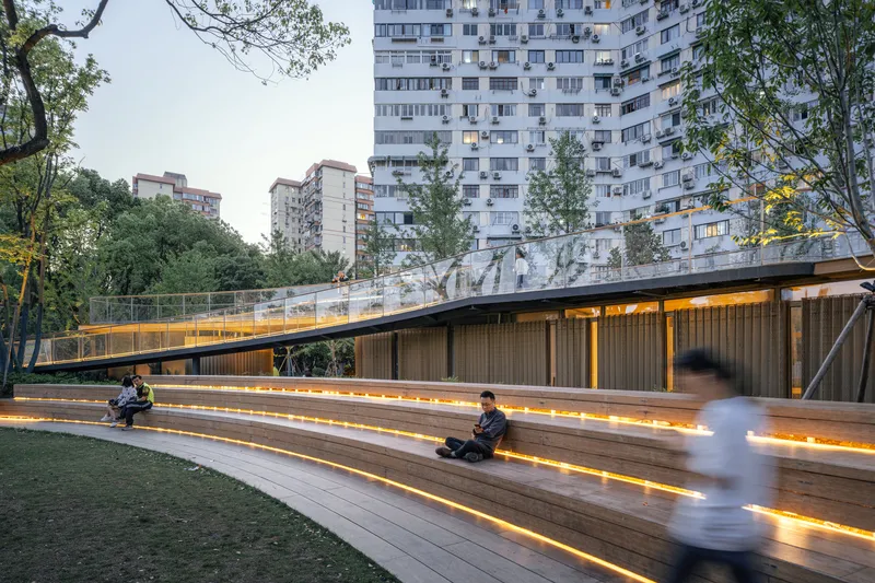 Timber amphitheater seating with integrated LED strip lighting at dusk with residential towers rising behind