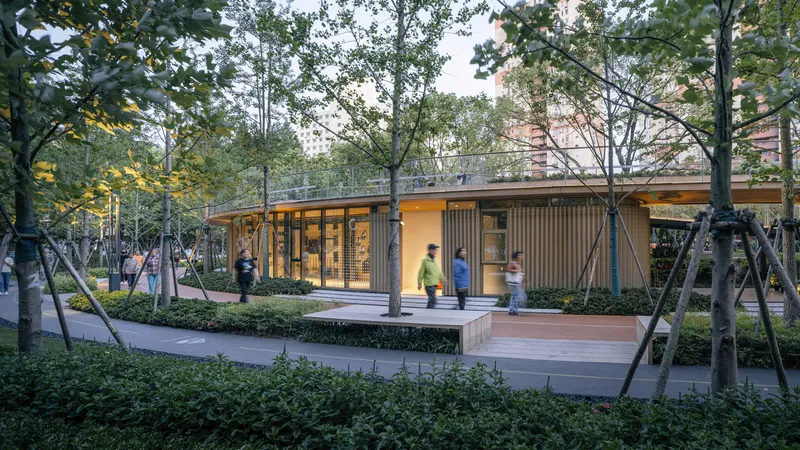 Single-story pavilion with timber-slatted facade and glass walls set among trees at dusk