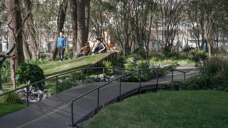 Timber bridge crossing a sunken path with steel railings and visitors seated on grassy banks
