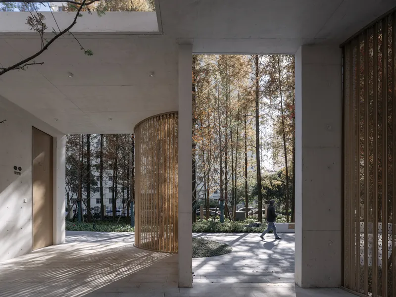 Interior corridor with curved wooden screen panels looking out to a wooded landscape beyond