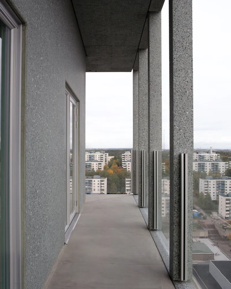 Narrow balcony with exposed aggregate concrete columns and residential blocks visible in the distance