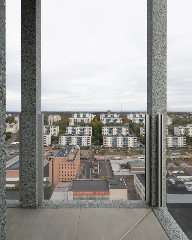 View through balcony columns framing residential blocks and autumn foliage below