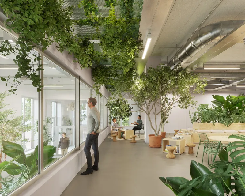 Office interior with potted trees, exposed ducts and a figure standing at the glazed partition wall
