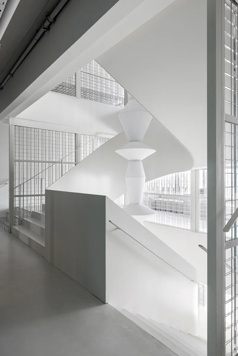 Double-height atrium with helical white staircase and glass block walls filtering daylight