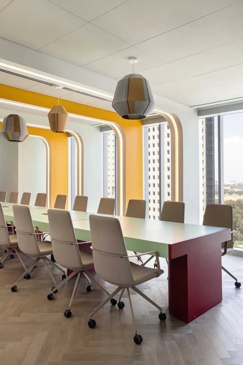 Conference room with arched yellow accent wall and faceted pendant lights above a mint green table
