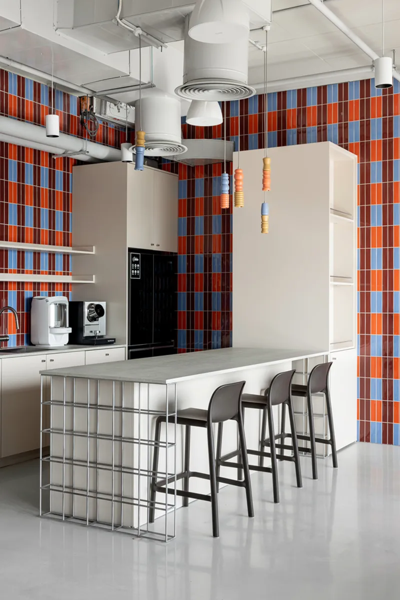 Kitchen island with glass block base surrounded by bar stools under exposed ceiling ductwork