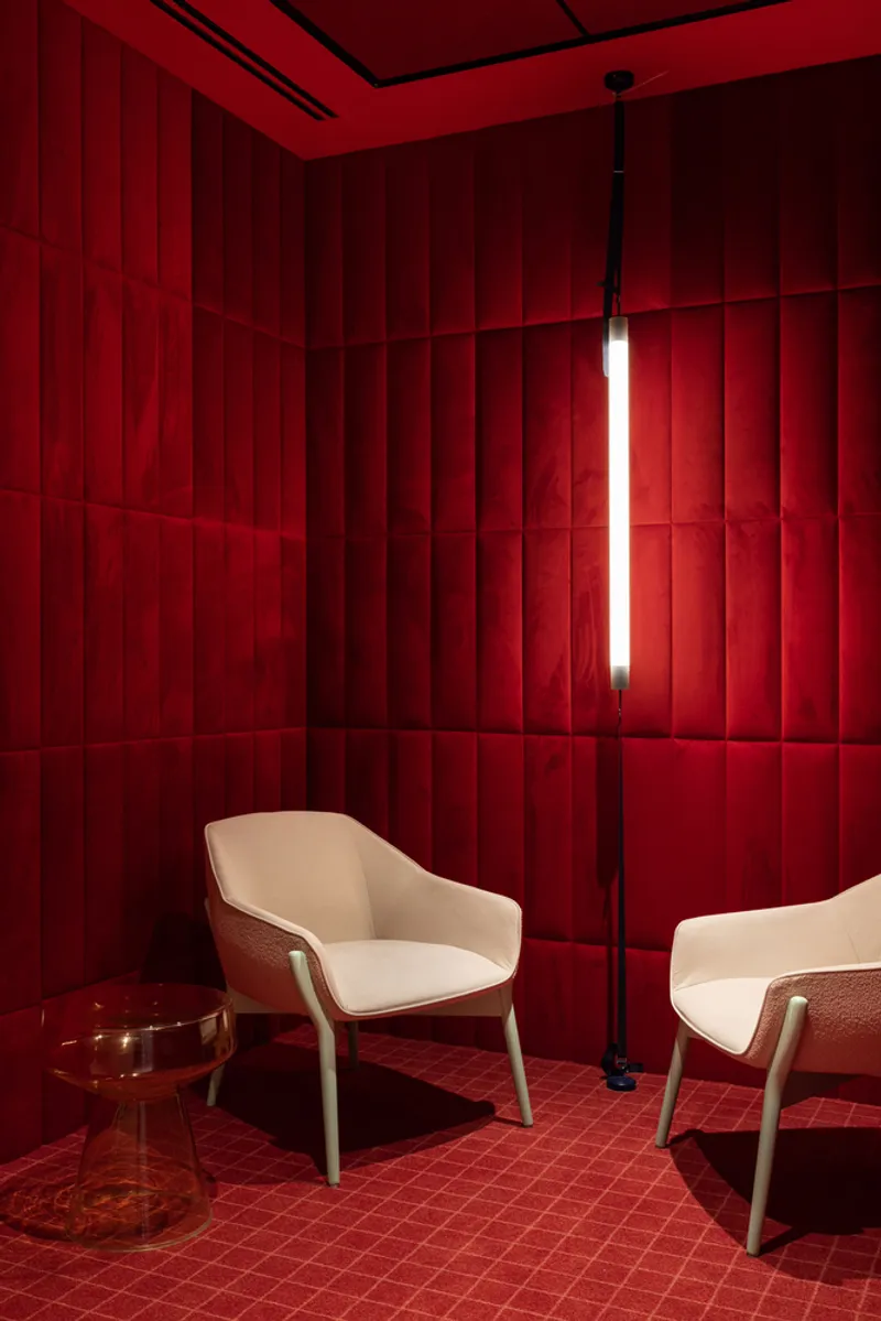 Red upholstered room with vertical paneled walls, a floor lamp, and cream armchairs