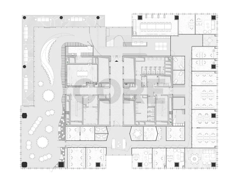 Floor plan drawing showing curved central staircase and scattered workstations within an irregular perimeter with outdoor terrace