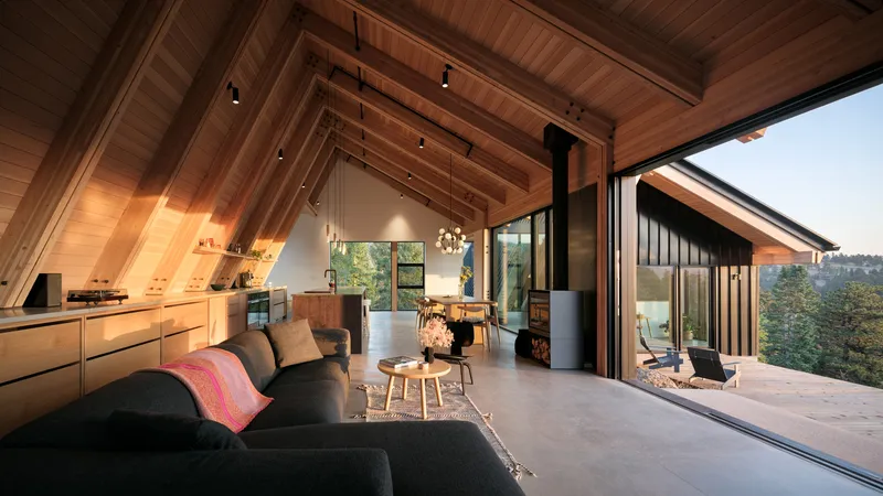 Open living space with exposed timber rafters and folding glass wall opening to terrace at dusk