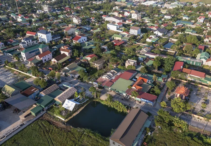 Aerial view of a residential neighborhood with varied roof colors and a central pond