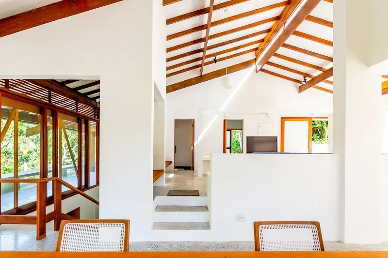 Interior view of exposed timber roof beams spanning above split-level terrazzo floors and white walls