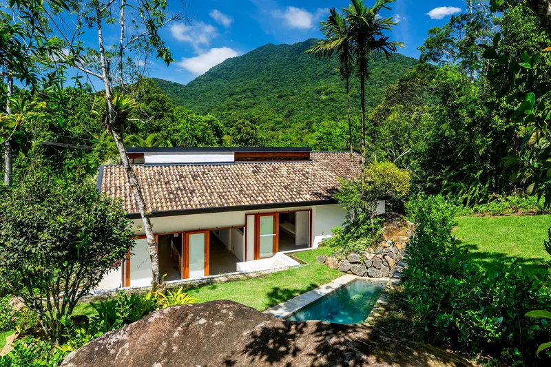 Aerial view of clay tile roof and courtyard pool set against forested mountain slopes