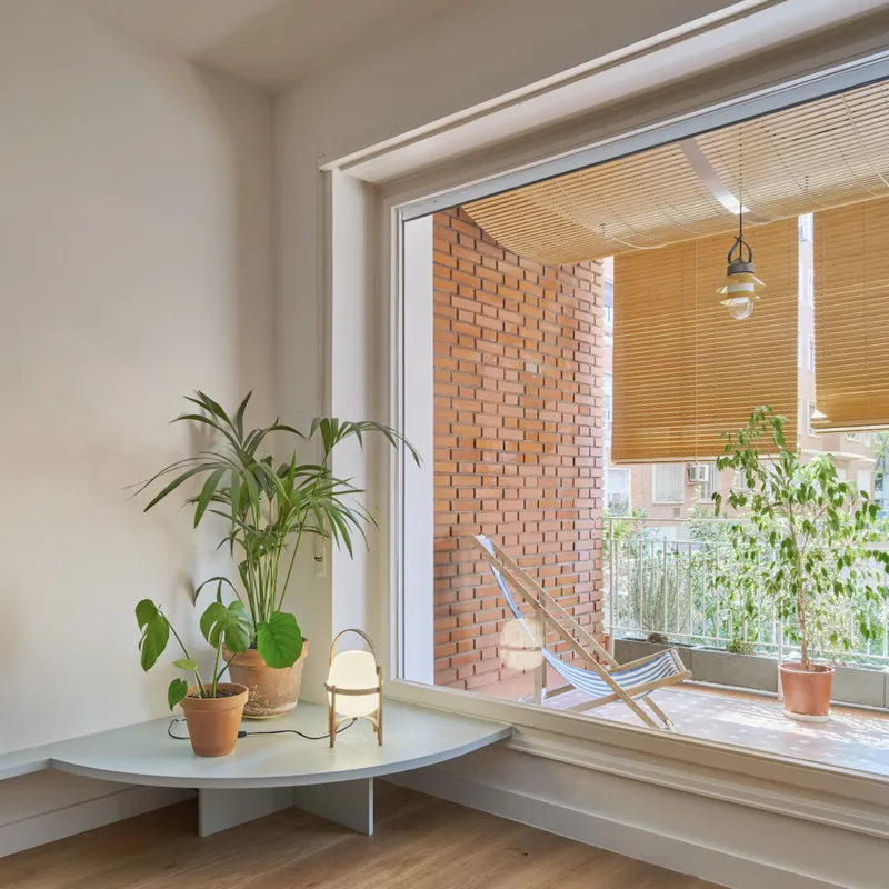 Interior window alcove with potted plants opening onto a balcony with perforated brick wall and slatted ceiling