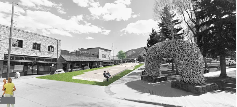 View along the elevated green promenade with the woven antler arch and seated visitors