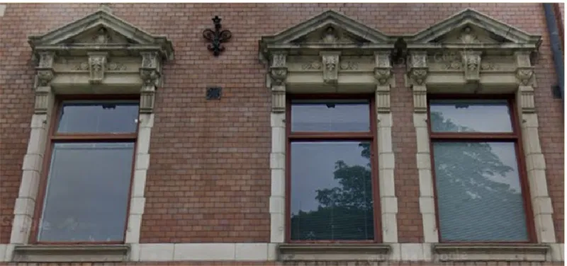 Three windows with stone pediments and decorative keystones set into a red brick facade