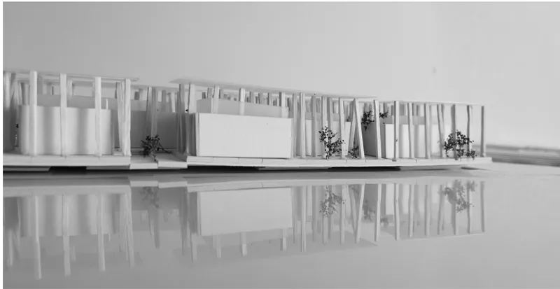 Physical model elevation showing the colonnade structure with varied column spacing and planted areas reflected on a mirrored surface