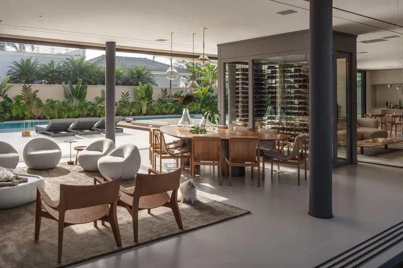 Open-plan living and dining space with cylindrical black columns opening to pool and garden