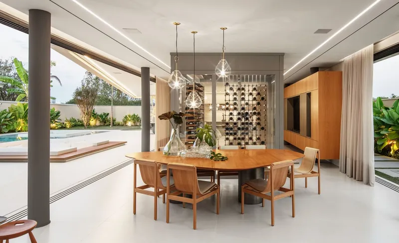 Open dining area with timber table and columns framing a pool terrace and tropical planting