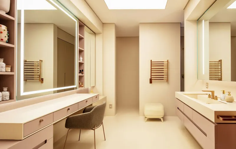 Dressing room with backlit mirrors, skylight above, and vanity desk with upholstered chair