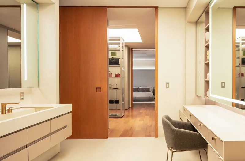 View through sliding wood door from vanity area into bedroom with timber flooring