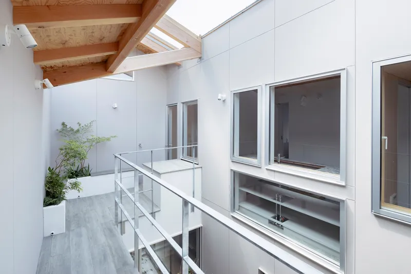 Interior courtyard walkway with glass railing and exposed timber roof beams under a skylight