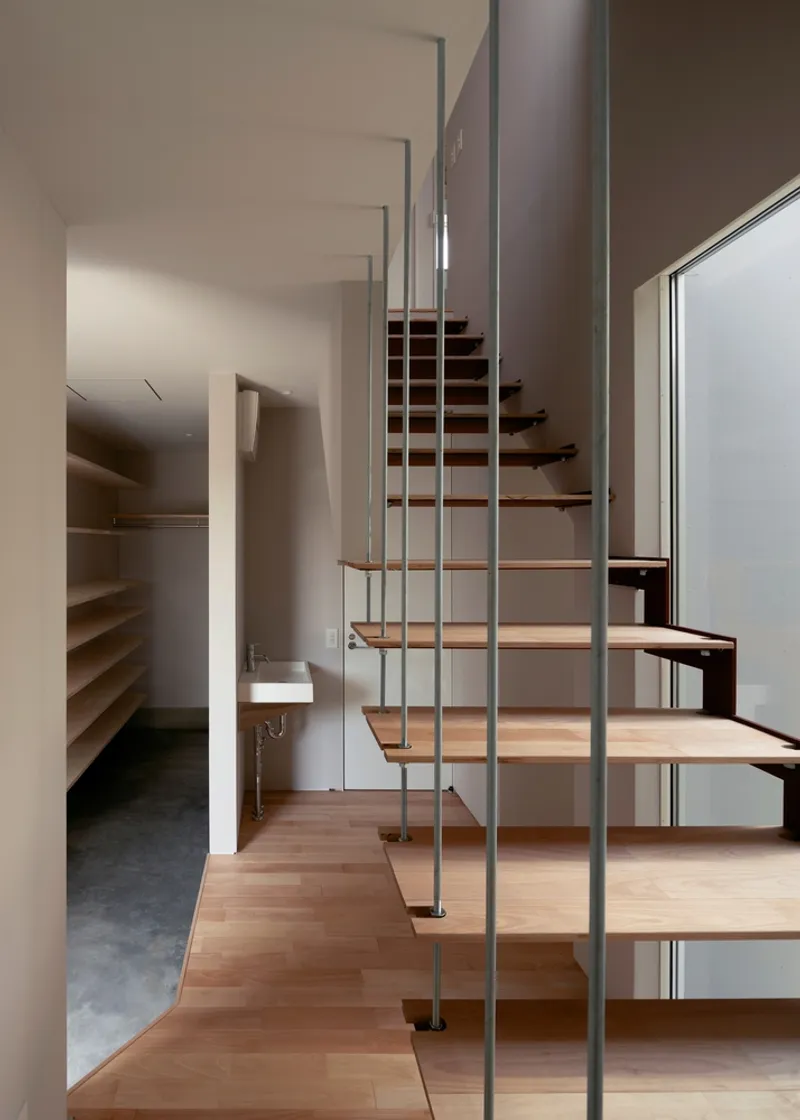 Open-tread timber staircase with vertical steel rod balustrade beside a small wall-mounted sink