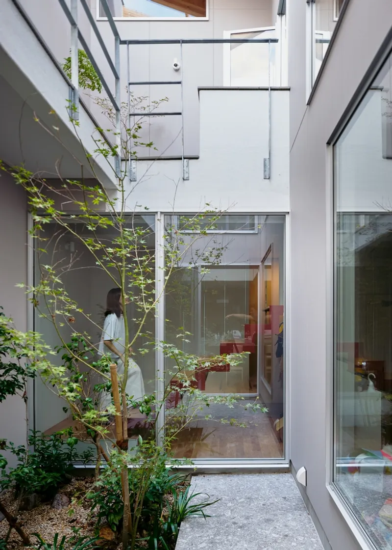 Internal courtyard with young tree plantings surrounded by glazed walls and steel stair landings above