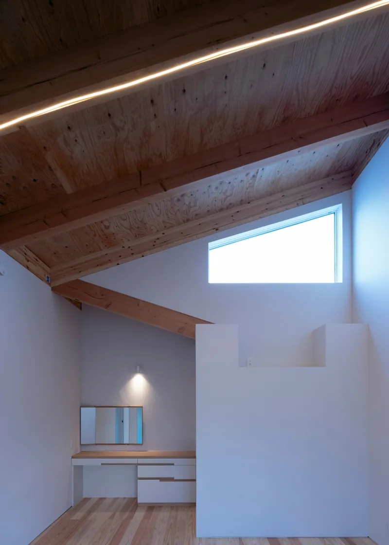Sloped timber ceiling with linear lighting and clerestory window above a built-in desk