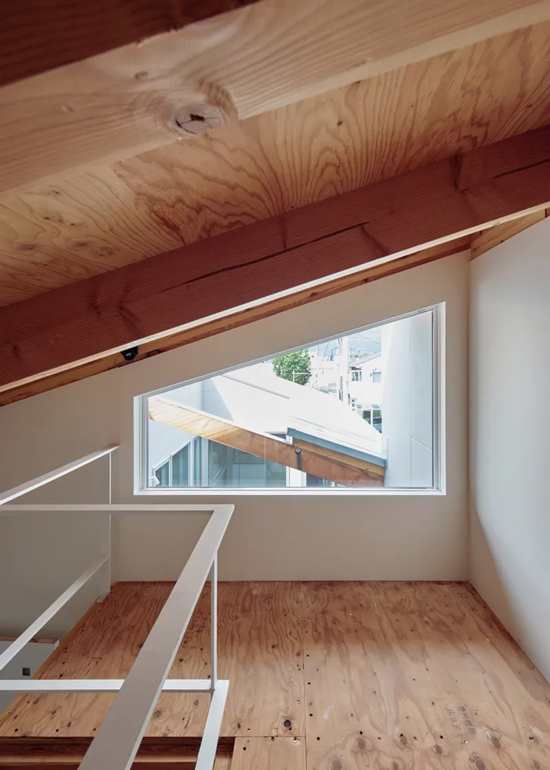 Upper floor corridor with horizontal window framing views across adjacent timber roofs