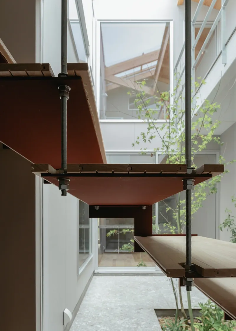 Close view of cantilevered steel and timber stair treads overlooking the planted courtyard below