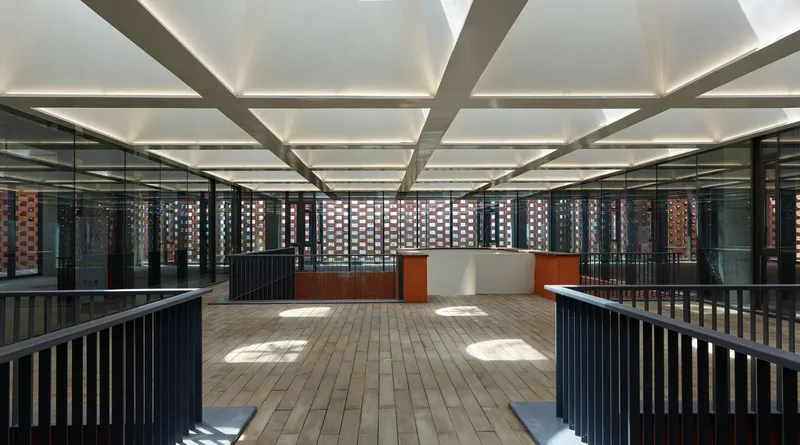 Covered balcony with timber flooring, grid ceiling and perforated brick screen walls in dappled sunlight