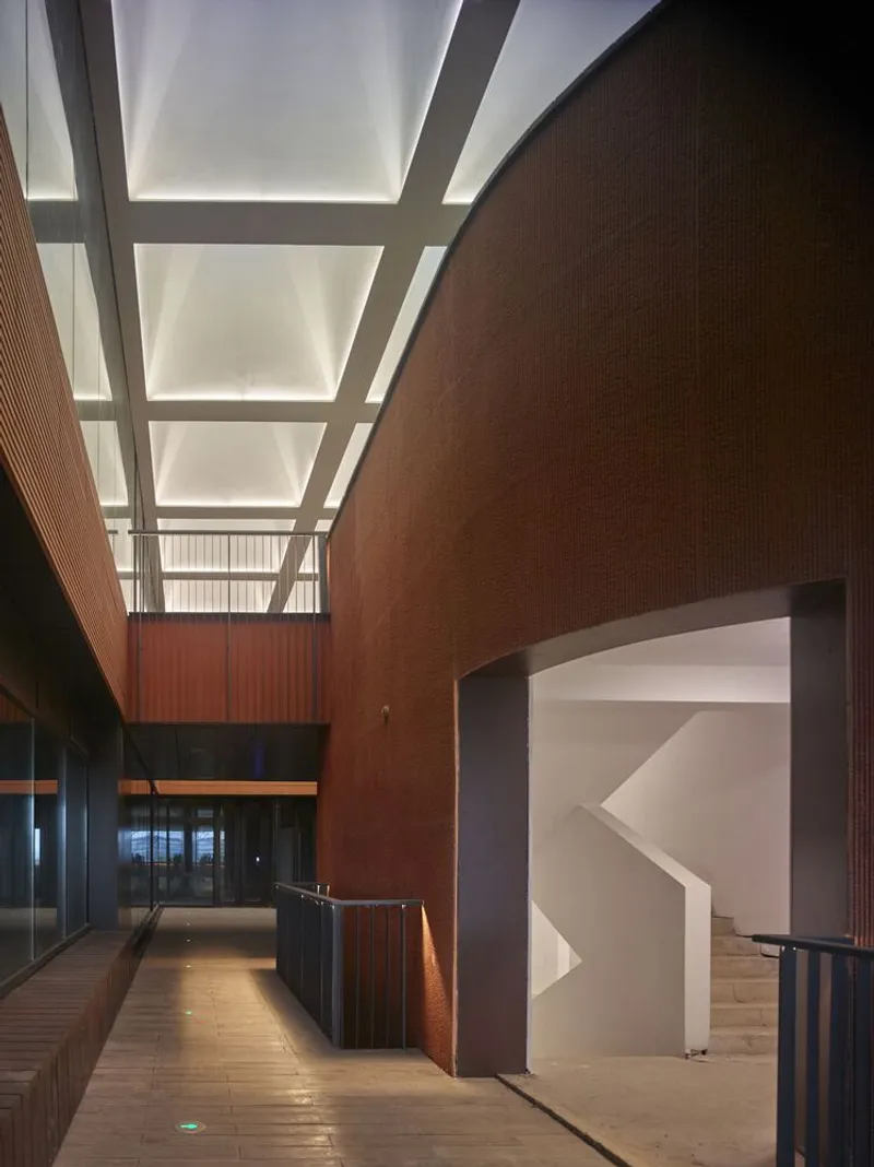 Interior corridor with red brick walls and translucent skylight panels casting soft light onto timber flooring