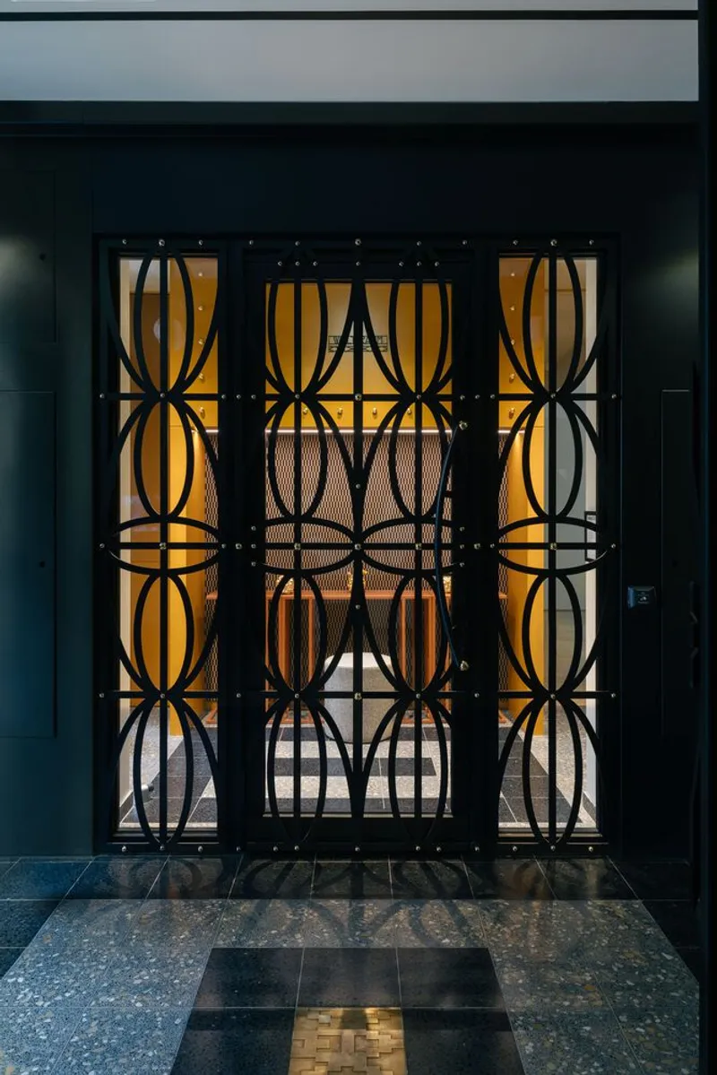 Decorative metal screen with circular pattern over amber-lit entrance and mosaic tile threshold