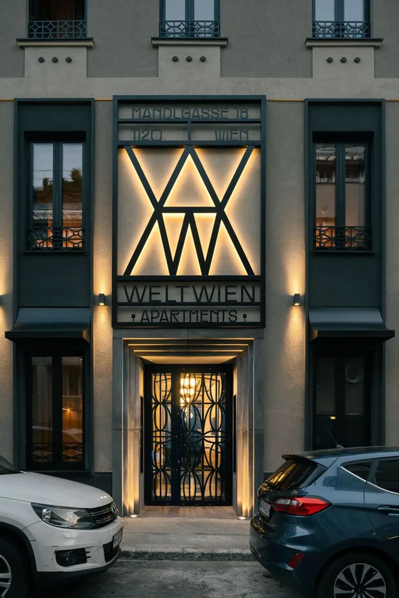 Entrance facade with decorative metalwork gate and glowing signage panel at evening
