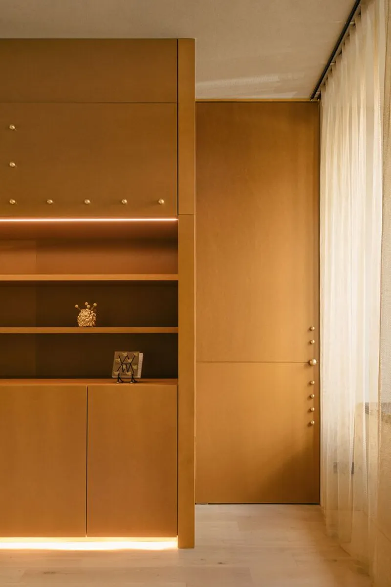 Wood-paneled entryway with built-in shelving and brass hardware illuminated by linear LED strip lighting