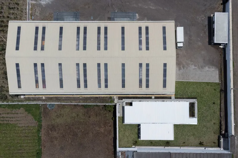Aerial view of the corrugated metal roof with vertical window strips and adjacent white courtyard volume